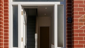 A modern entrance with a glass door, a wooden staircase, and a brick exterior. - 4-BR Liverpool House Free Parking (Liverpool)