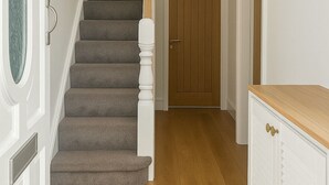A staircase leading to a wooden door, a white cabinet with a wooden countertop, and a light switch on the wall. - 4-BR Liverpool House Free Parking (Liverpool)