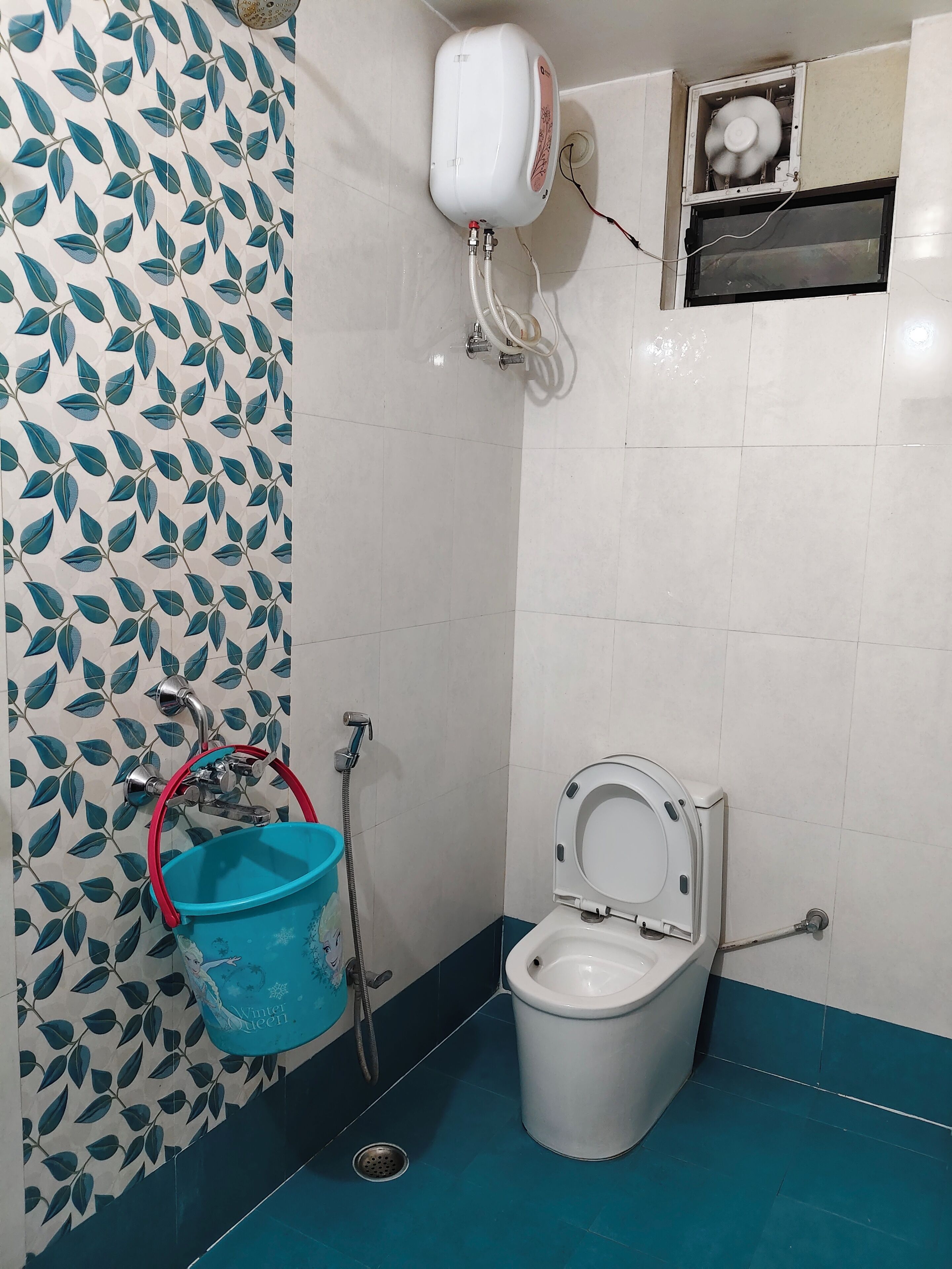 A bathroom with a toilet, a blue bucket, a shower, and a wall-mounted heater.