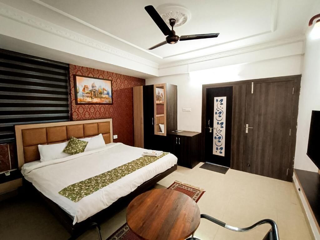 A hotel room with a bed, a ceiling fan, a desk, and a wardrobe.