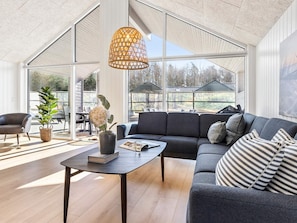 A modern living room with a sofa, a coffee table, and a hanging light fixture. - 5 Star Holiday Home in Glesborg (Glesborg)