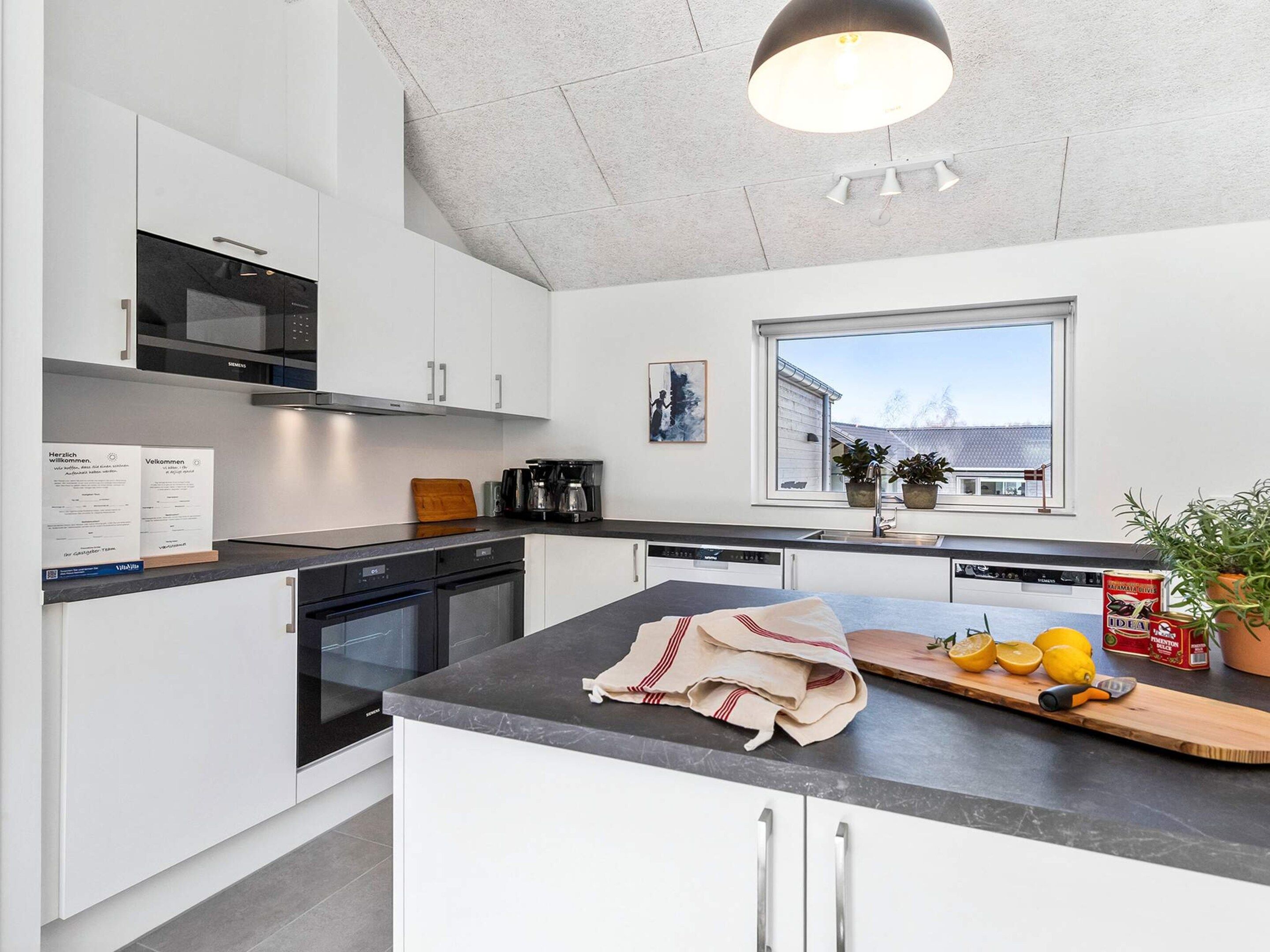 Una cucina moderna con mobili bianchi, un piano di lavoro nero e una finestra che offre vista all'esterno.