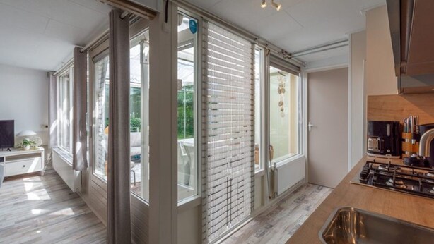 A modern kitchen with a stainless steel sink, a built-in stove, and a window with blinds. - Spacious Duinland 188 Home With Veranda (Sint Maartensvlotbrug)