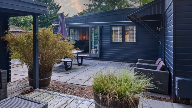 A patio with a table and chairs, a covered seating area, and potted plants. - Cozy forest cottage - cozy wooden cottage in the middle of nature on the Veluwe (Putten)