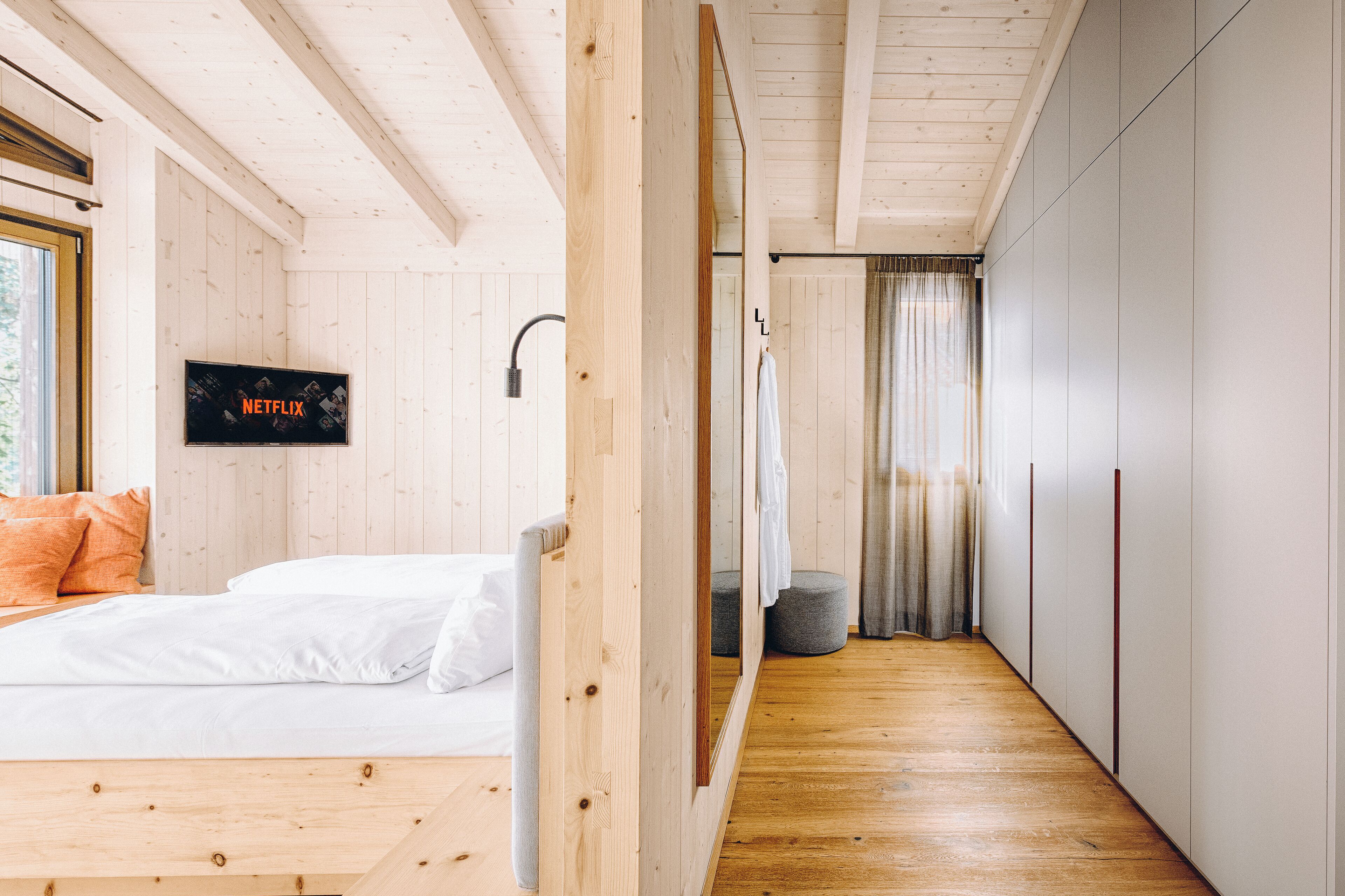 Una camera da letto moderna con un letto in legno, una TV a parete e un cabina armadio.