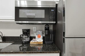 Une cuisine équipée d’un four à micro-ondes en acier inoxydable, d’une machine à café et d’un distributeur de capsules de café.