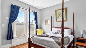 Una cama con dosel, un cabecero, una mesita de noche con una lámpara y una silla.