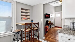Una cocina con comedor, un televisor montado en la pared y una ventana con persianas.
