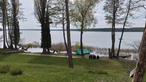 Vista su un lago con alberi, una tenda e una zona erbosa.