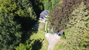 An aerial view of a house surrounded by dense forest, with a visible deck and a driveway leading to the entrance. - La Bellevue forest-edge cottage (Hénouville)