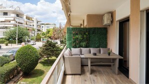 Een balkon met een bank, tafel en een groene wand.