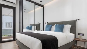 Een moderne slaapkamer met een groot bed, een klein nachtkastje en een grote spiegel.