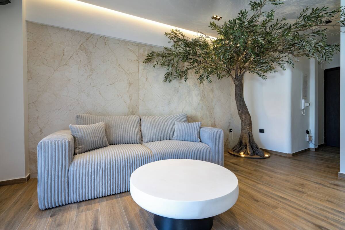 Ein modernes Wohnzimmer mit einer Couch, einem runden Couchtisch und einer Baumskulptur.