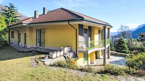 Une maison à deux étages avec une façade jaune, un toit recouvert de tuiles rouges et un balcon.
