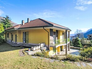A two-story house with a yellow facade, a red-tiled roof, and a balcony. - Lovely apartment for 6 guests with WIFI, TV and terrace (Mergozzo)