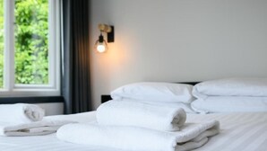 A neatly made bed with white towels and a wall-mounted light fixture. - The Righ (Oban)