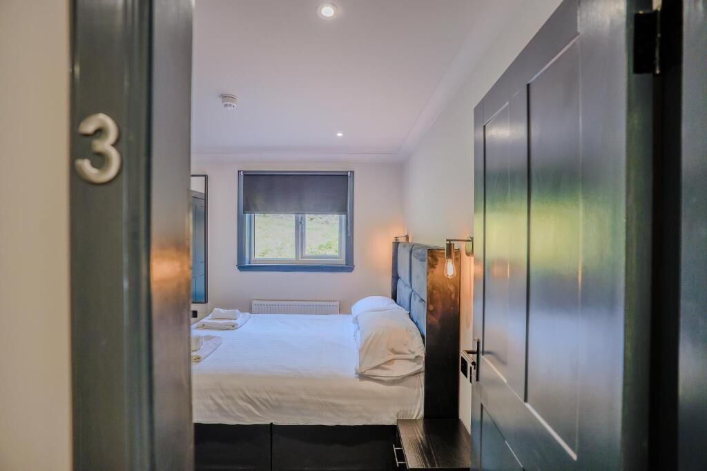 Una habitación de hotel con una cama, una ventana y una puerta con el número 3.