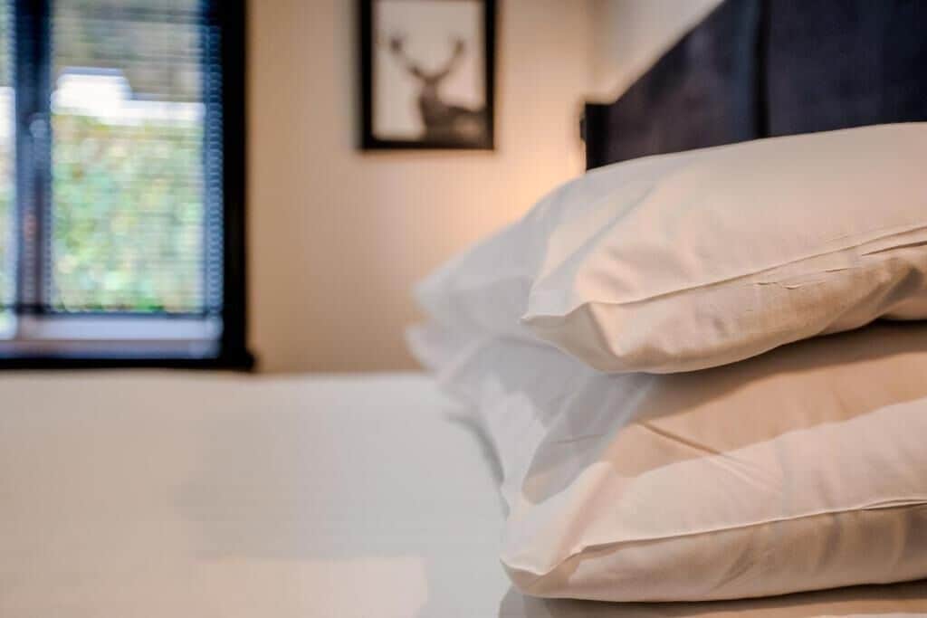 A neatly made bed with multiple pillows and a framed picture on the wall.