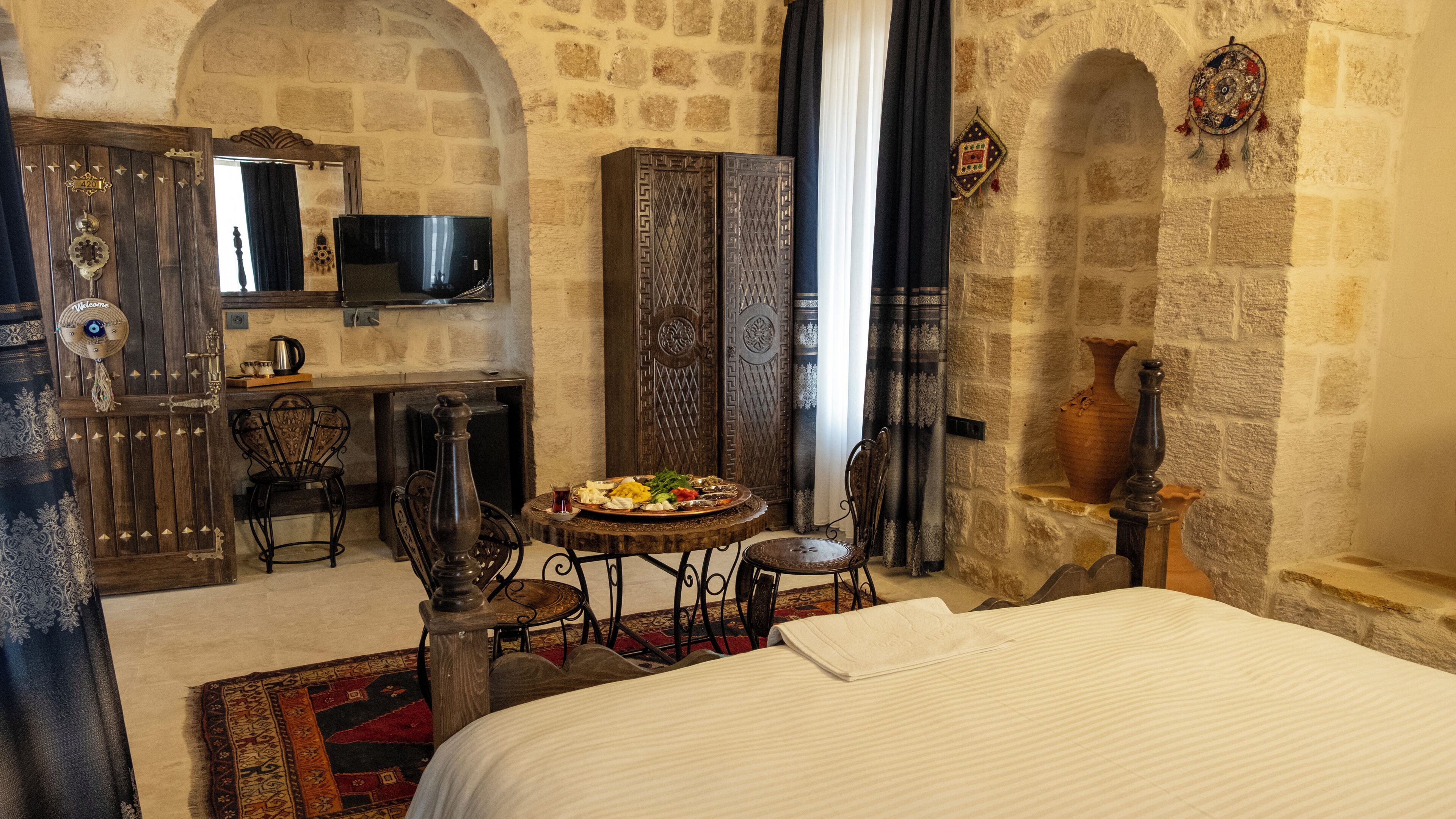 Una habitación tradicional con cama, una mesita redonda con comida, televisor y armario.