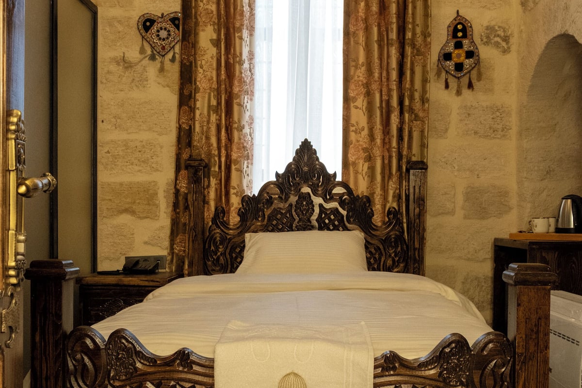 A traditional wooden bed with a decorative headboard, a bedside table, and a nightstand.