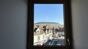 Ein Fenster mit Blick auf eine Straßenszene, darunter Gebäude und parkende Autos.