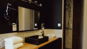Ein modernes Badezimmer mit einem schwarzen Waschbecken, einem Spiegel und einer Duschkabine.