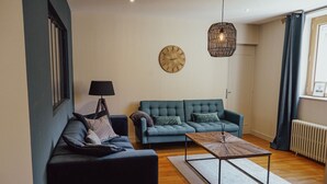 A living room with two sofas, a coffee table, a wall clock, and a hanging light fixture.