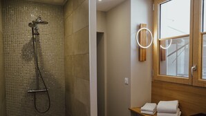 A bathroom with a shower, a wooden vanity, and a mirror with a wooden frame.