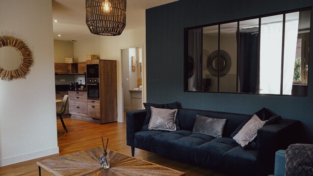 A modern living room with a dark blue sofa, a wooden coffee table, and a large mirror on the wall.