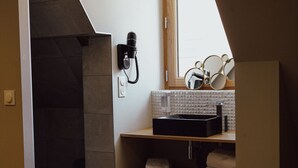 Une salle de bain moderne avec un lavabo noir, un porte-serviettes et un sèche-cheveux fixé au mur.