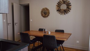 Un coin repas comprenant une table en bois, quatre chaises et deux miroirs fixés au mur.