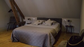 Une chambre à coucher comprenant un lit, deux tables de chevet, une chaise et un luminaire suspendu.