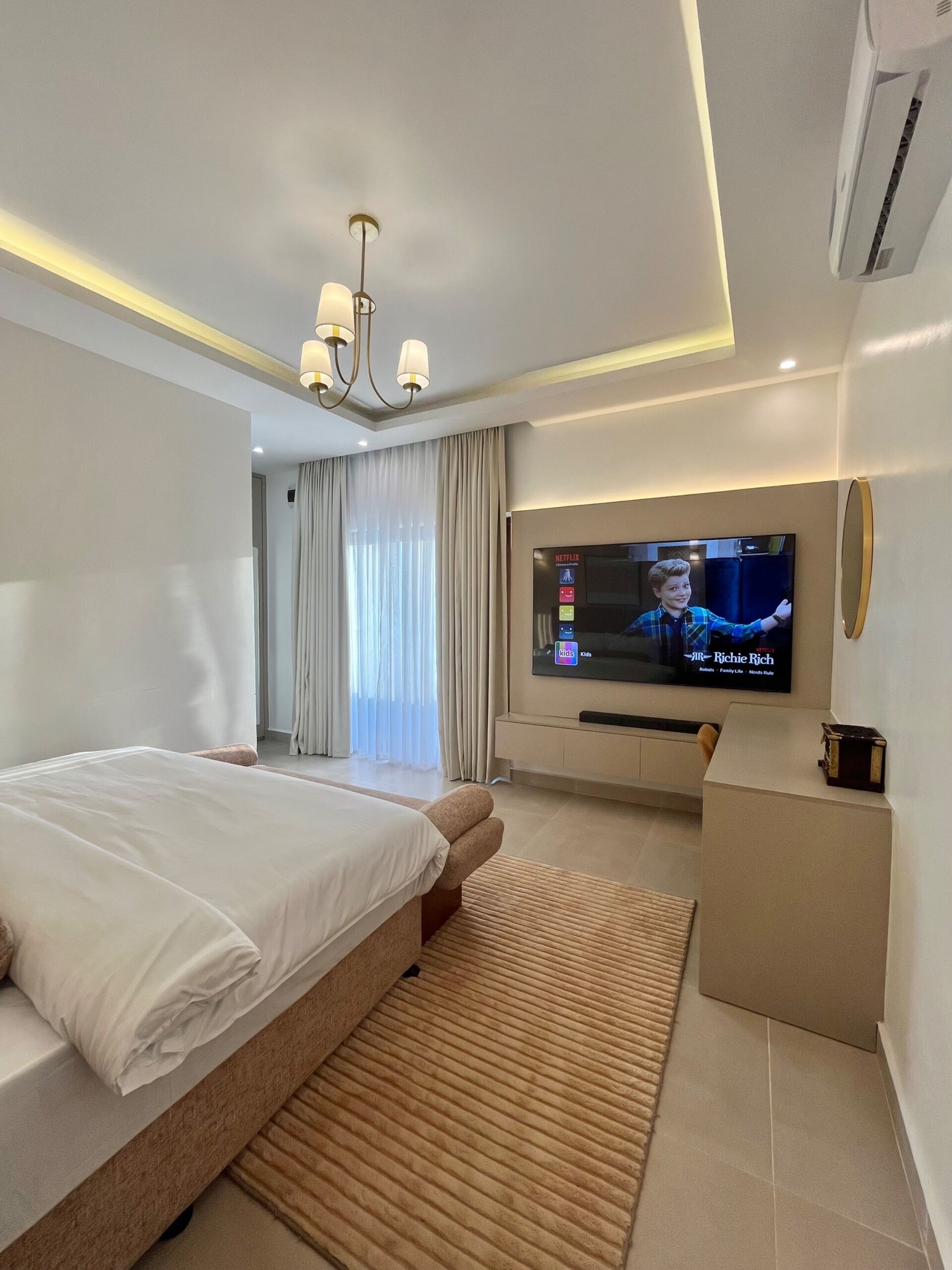 Una habitación de hotel moderna con una cama grande, un televisor montado en la pared y un escritorio pequeño.
