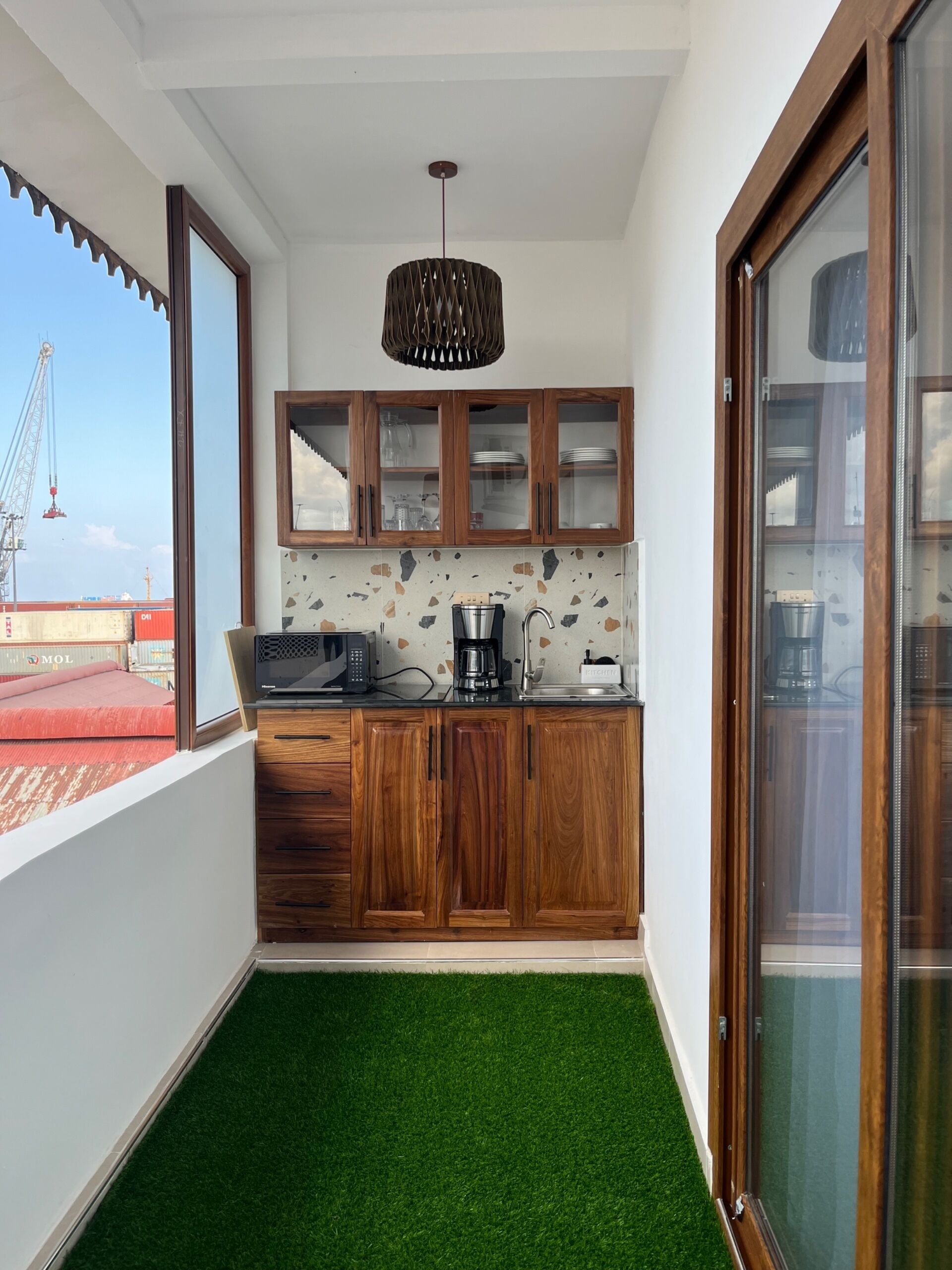 A small kitchen with wooden cabinets, a coffee maker, and a view of a construction site.