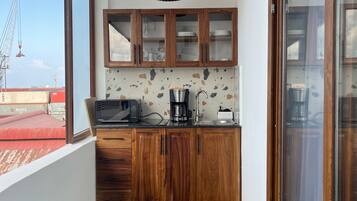 A small kitchen with wooden cabinets, a coffee maker, and a view of a construction site.