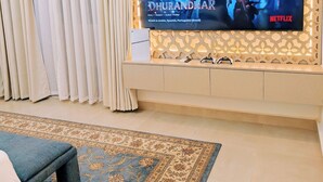 A living room with a large flat-screen TV mounted on a wall, a sofa, and a patterned rug. - ZAURA ZANZIBAR (Zanzibar Town)