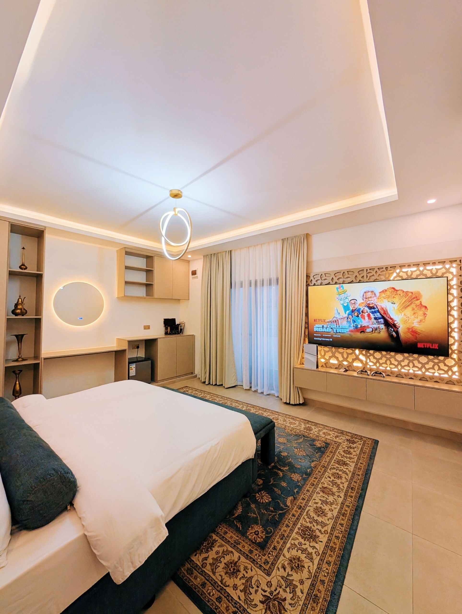 Una habitación de hotel moderna con una cama grande, televisión, escritorio y un adornado muro.
