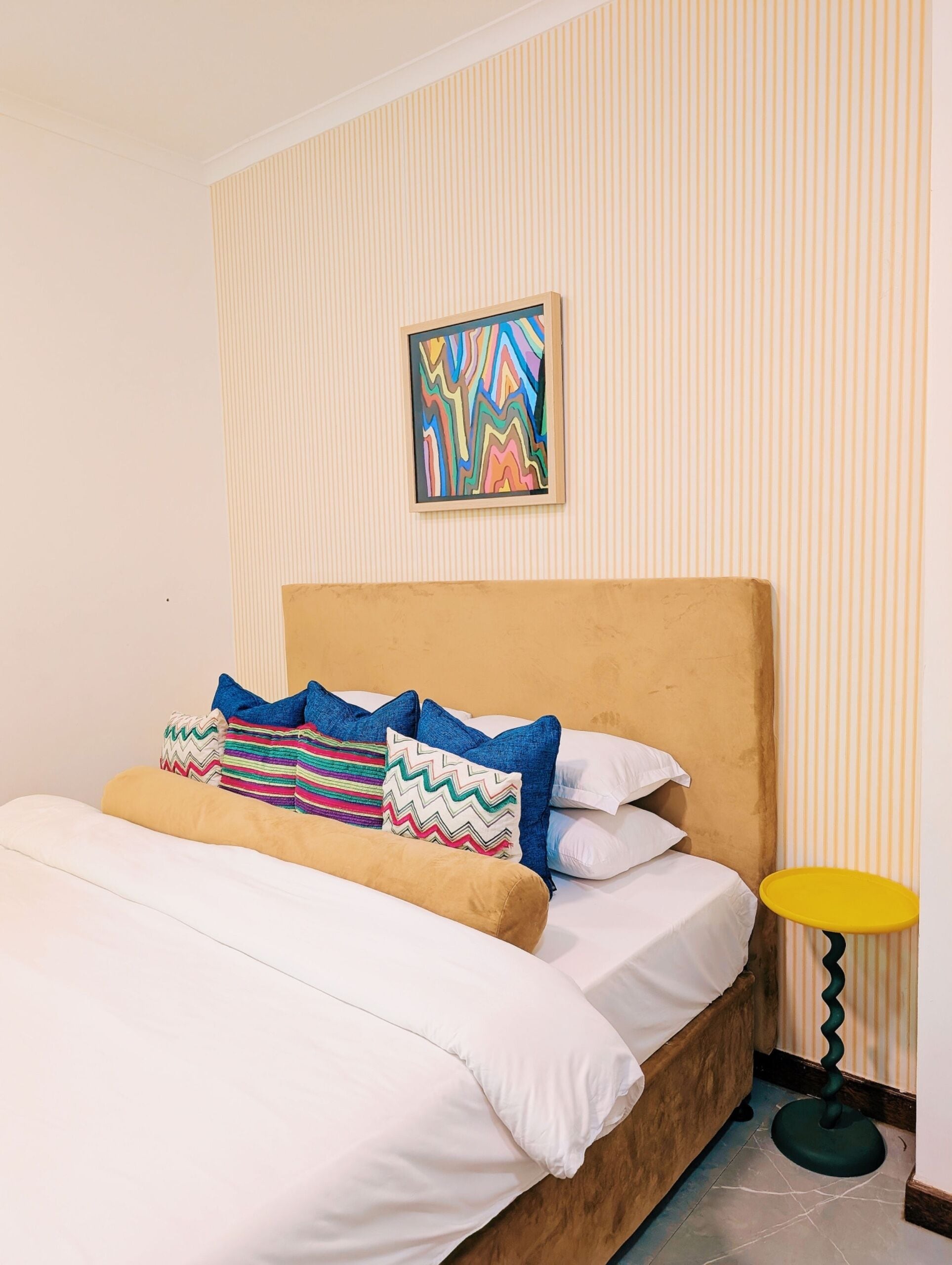 Una cama con sábanas blancas, cabecera de madera y almohadas coloridas.