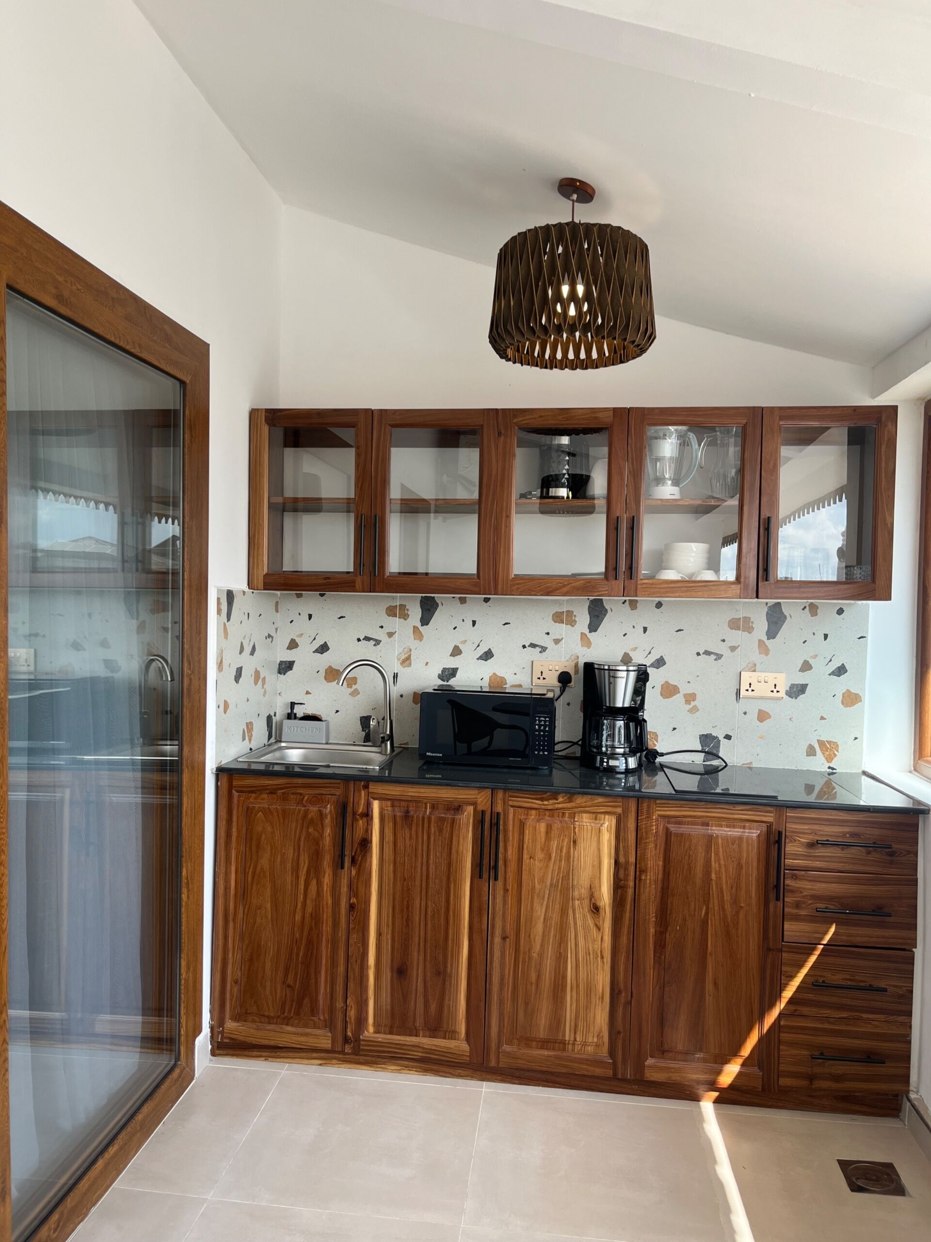 A modern kitchen with wooden cabinets, a glass backsplash, and a built-in microwave.