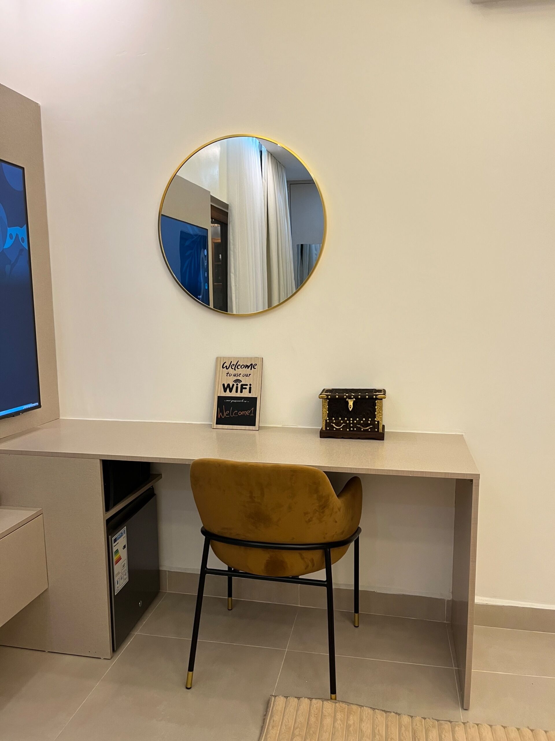 Un espacio de trabajo moderno con un espejo redondo, un escritorio, una silla e indicación de disponibilidad de WiFi.