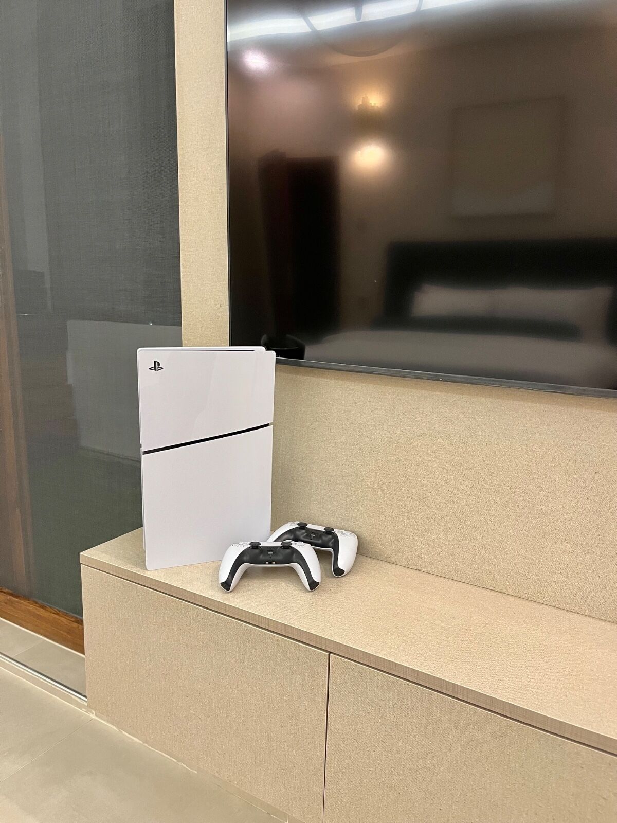 Un frigorifero bianco e due joystick per videogiochi su un piano di lavoro beige in una camera d'albergo.