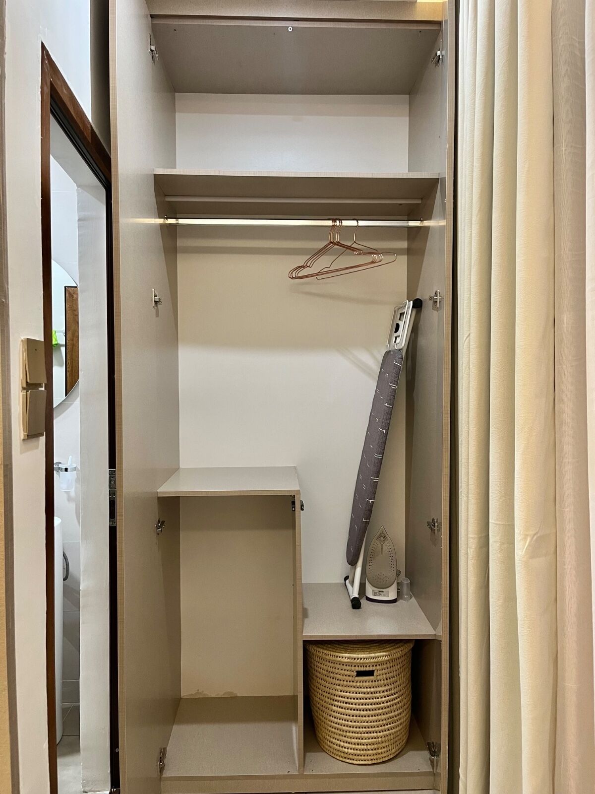 Ein begehbarer Kleiderschrank mit offenen Regalen, einer Kleiderstange und einem Korb.