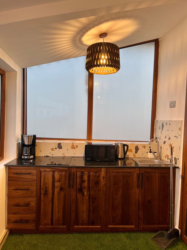 Una cocina con armarios de madera, microondas, cafetera y ventana con vistas.