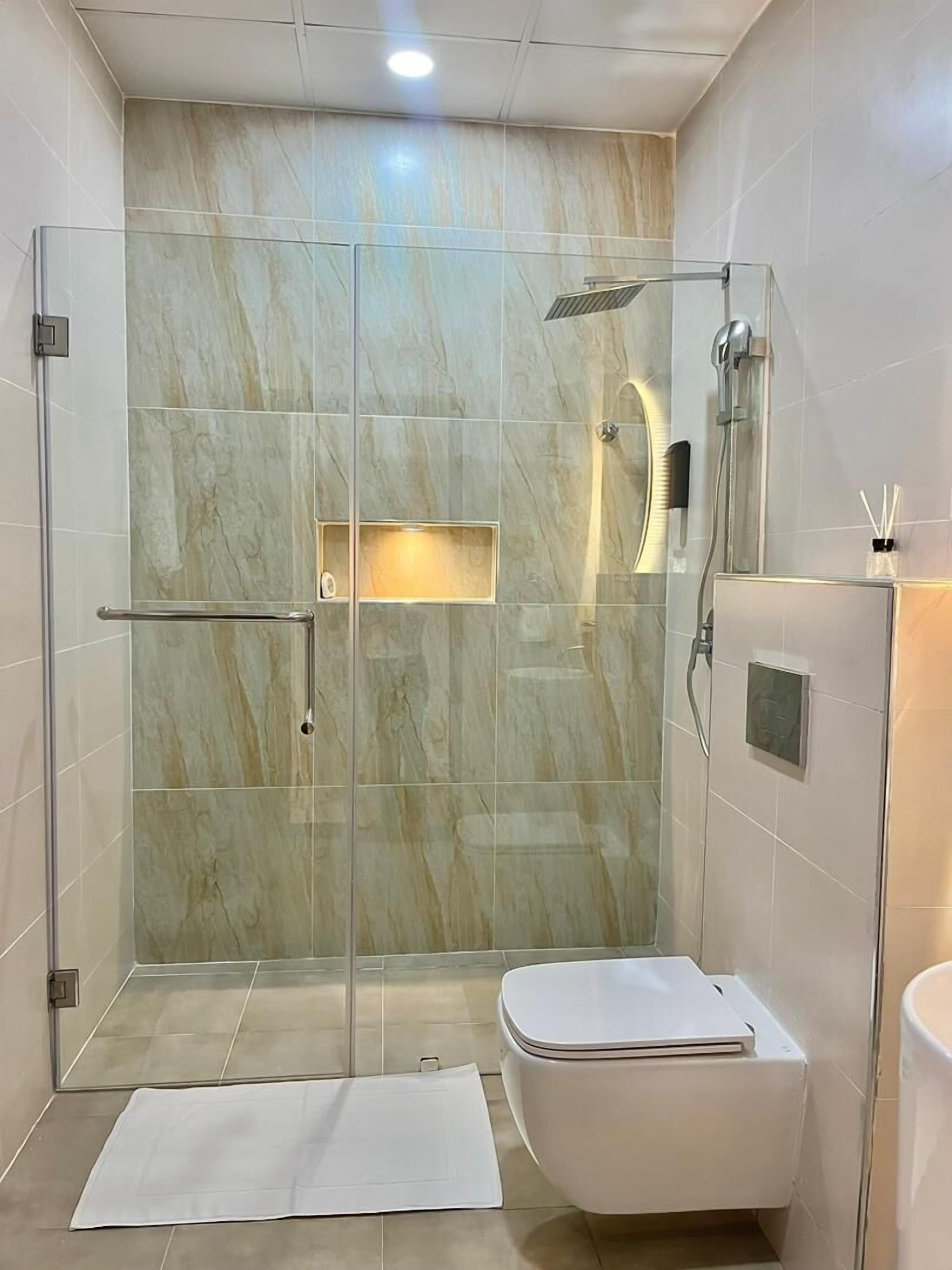 A modern bathroom with a glass-enclosed shower, a toilet, and a vanity with a mirror.