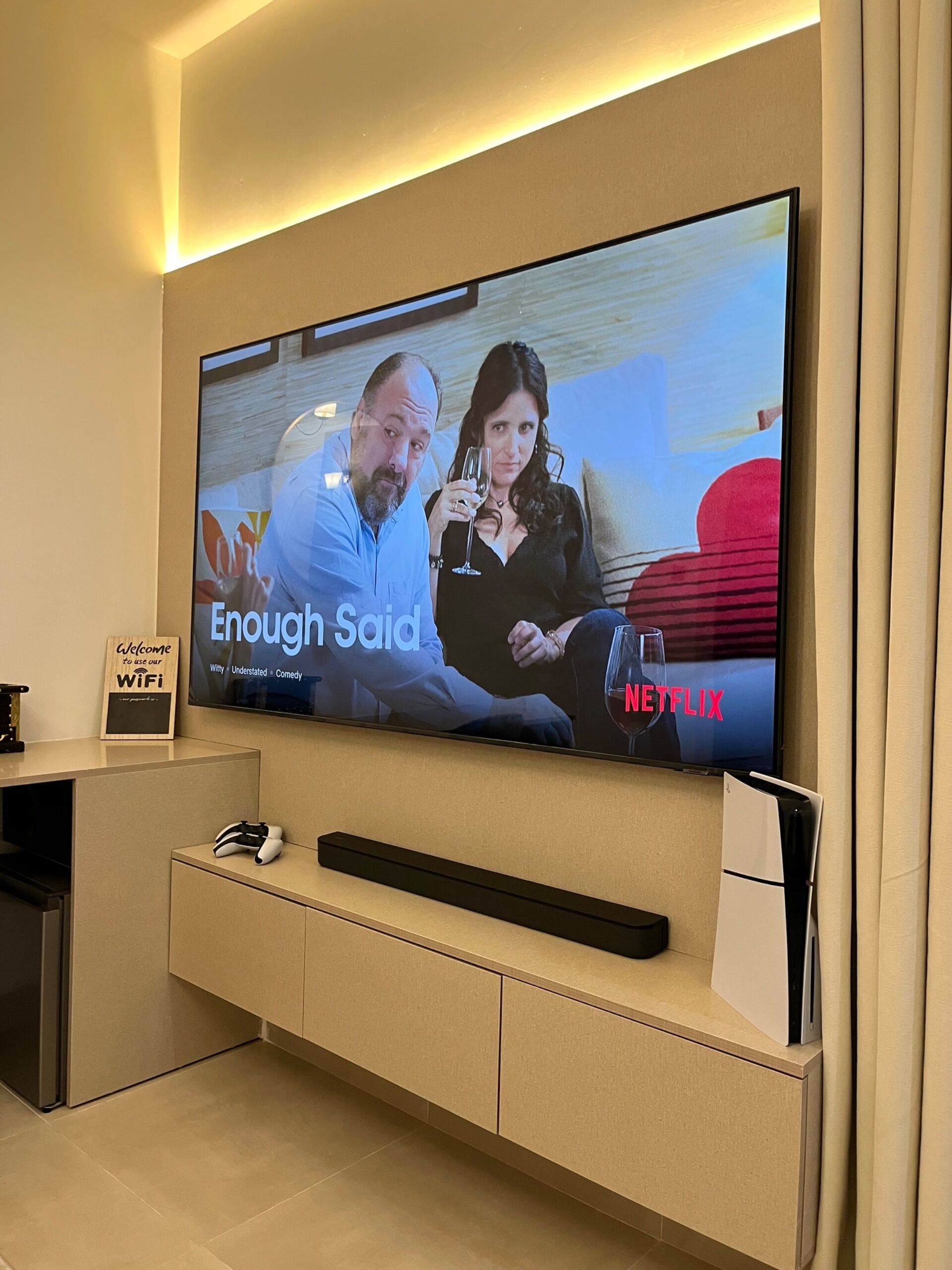 A flat-screen TV mounted on a wall, displaying a movie scene with the Netflix logo.