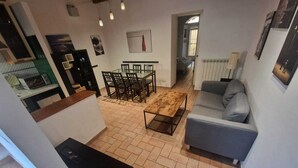 Un salon avec un canapé gris, une table basse en bois et un coin repas comprenant des chaises et une table.