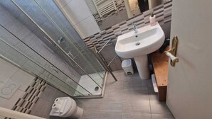 Une salle de bain moderne équipée d’une douche, de toilettes, d’un lavabo et d’une petite poubelle.