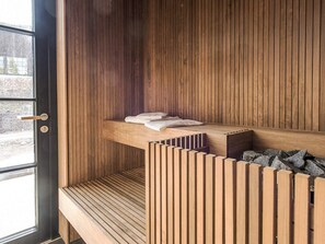A modern room with a wooden slatted bench, a small shelf with towels, and a window with a view of the outside. - 5 Star Holiday Home in Salen (Salen)
