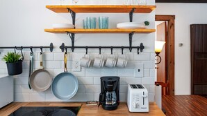 A kitchen with wooden shelves holding glassware, a coffee maker, and a toaster.