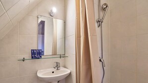 Een badkamer met een witte wastafel, een spiegel en een douche.